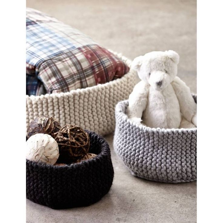 three crocheted baskets with stuffed animals in them and one is sitting on the floor