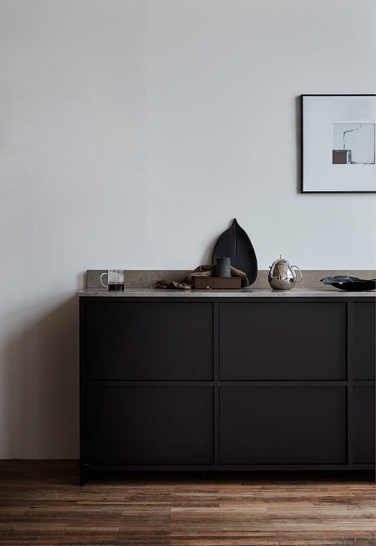 an empty room with a black cabinet and pictures on the wall above it, along with other items