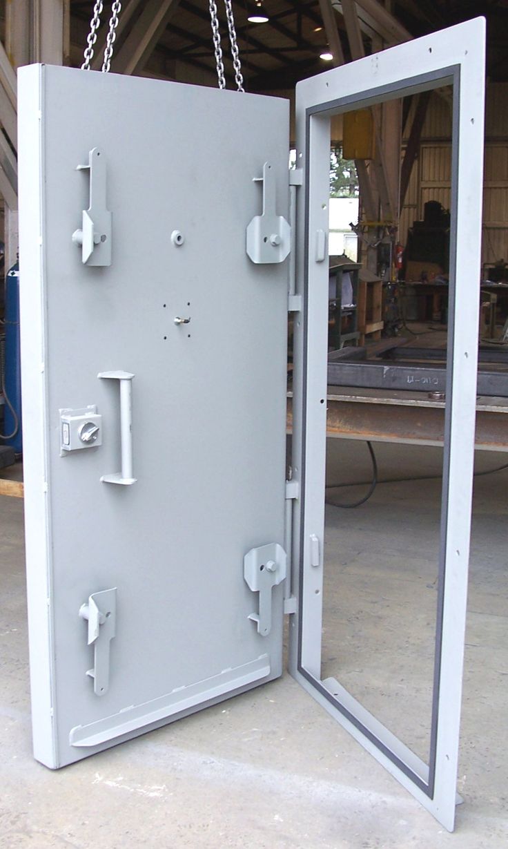 an open metal door with chains hanging from it's sides in a warehouse area