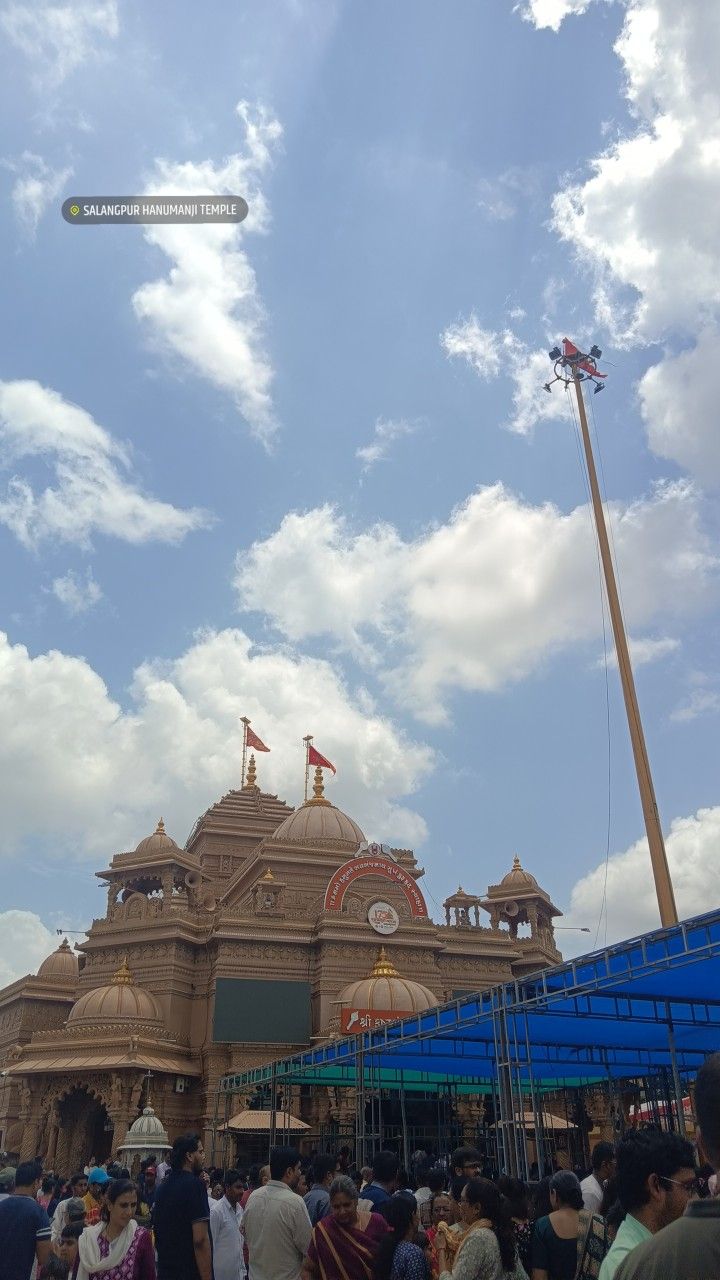 a crowd of people standing in front of a building under a blue sky with clouds