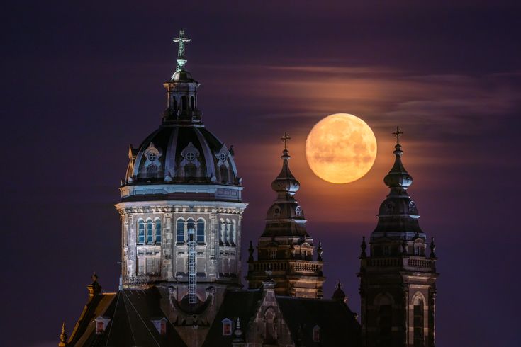 the full moon is setting over some buildings