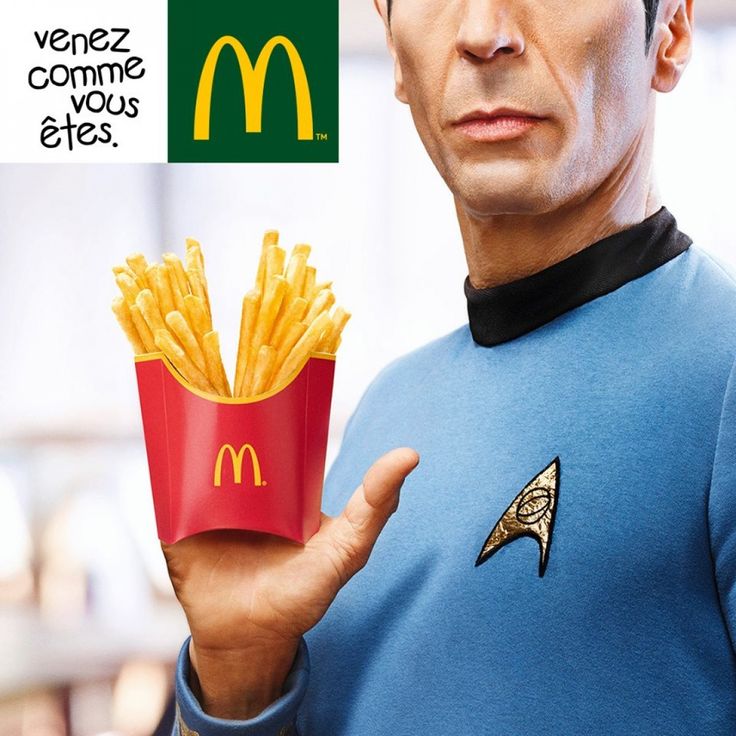 a man in a star trek uniform holding a box of french fries with the caption's logo on it