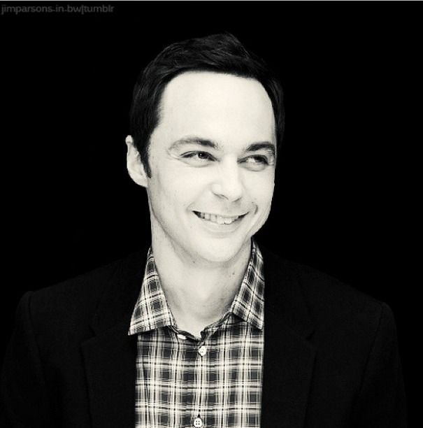 a black and white photo of a man with a smile on his face wearing a plaid shirt