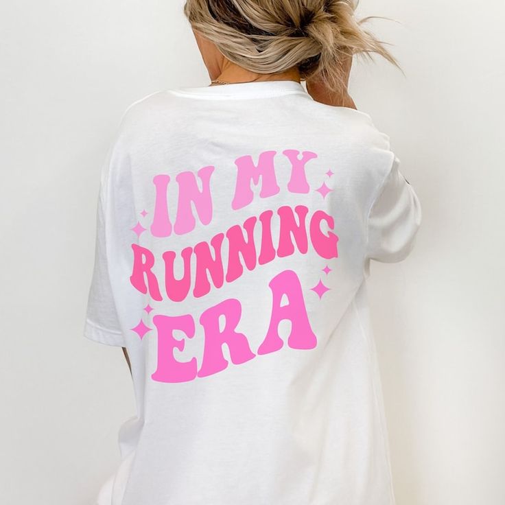 a woman with her back to the camera wearing a white shirt that says in my running era