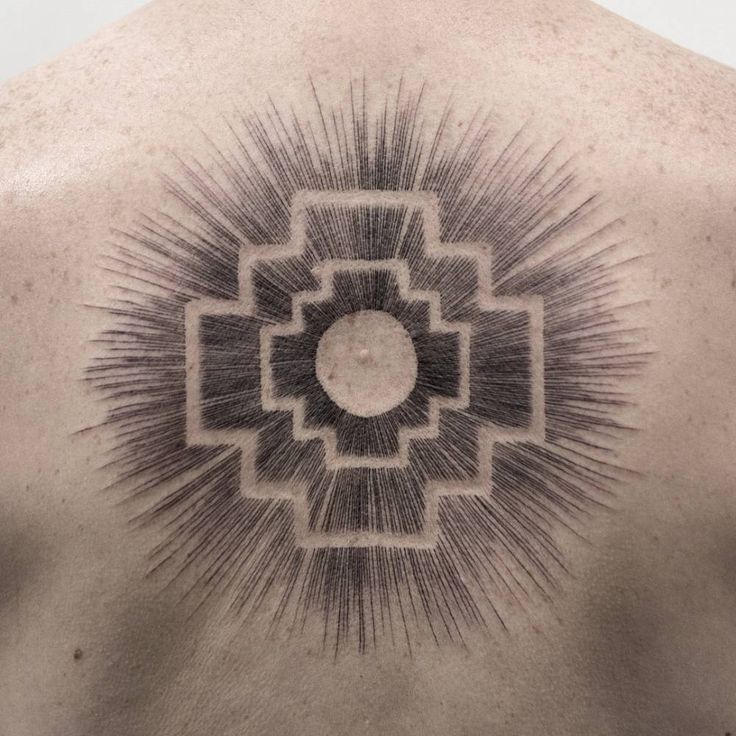 the back of a man's neck with an intricate tattoo design on his chest