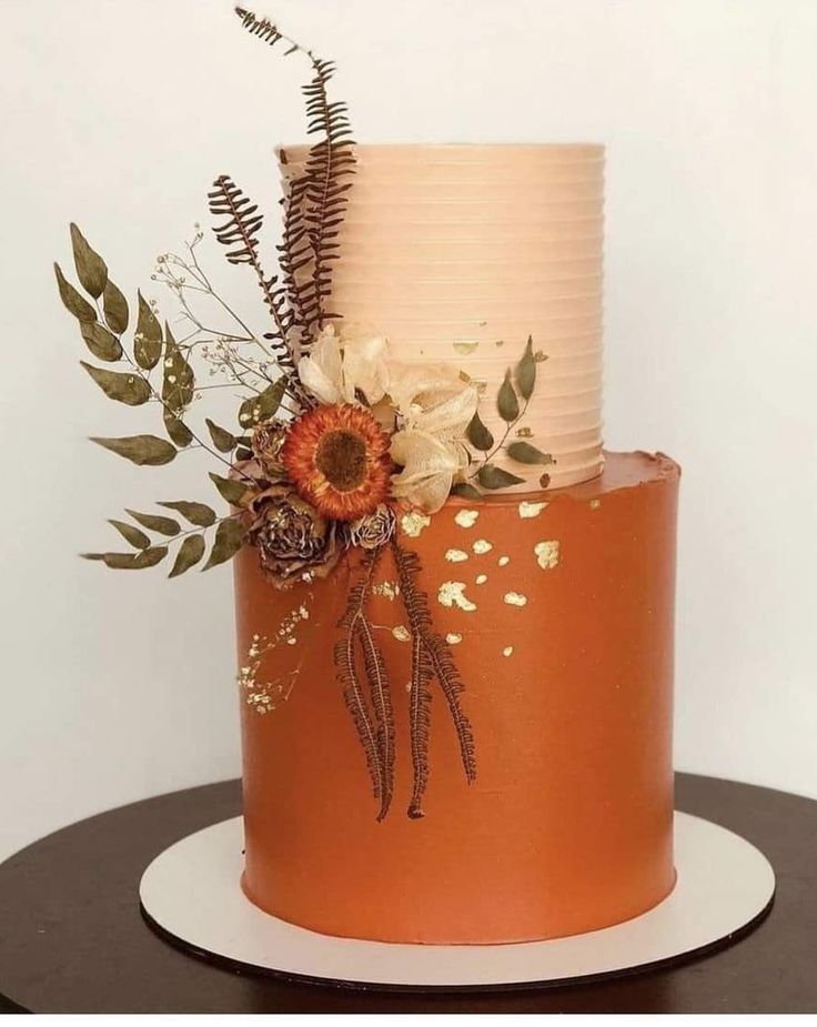 a three tiered cake decorated with flowers and leaves