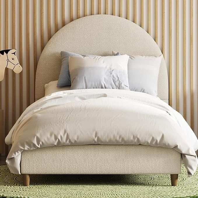 a bed with white sheets and pillows on top of it next to a green rug