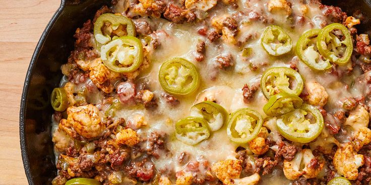 a casserole dish with sausage, cheese and green bell peppers on the side