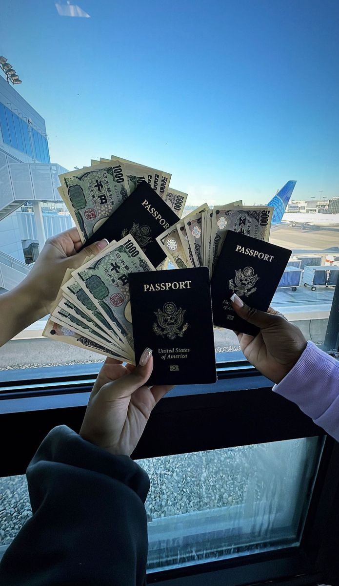 two people holding passport cards in front of a window