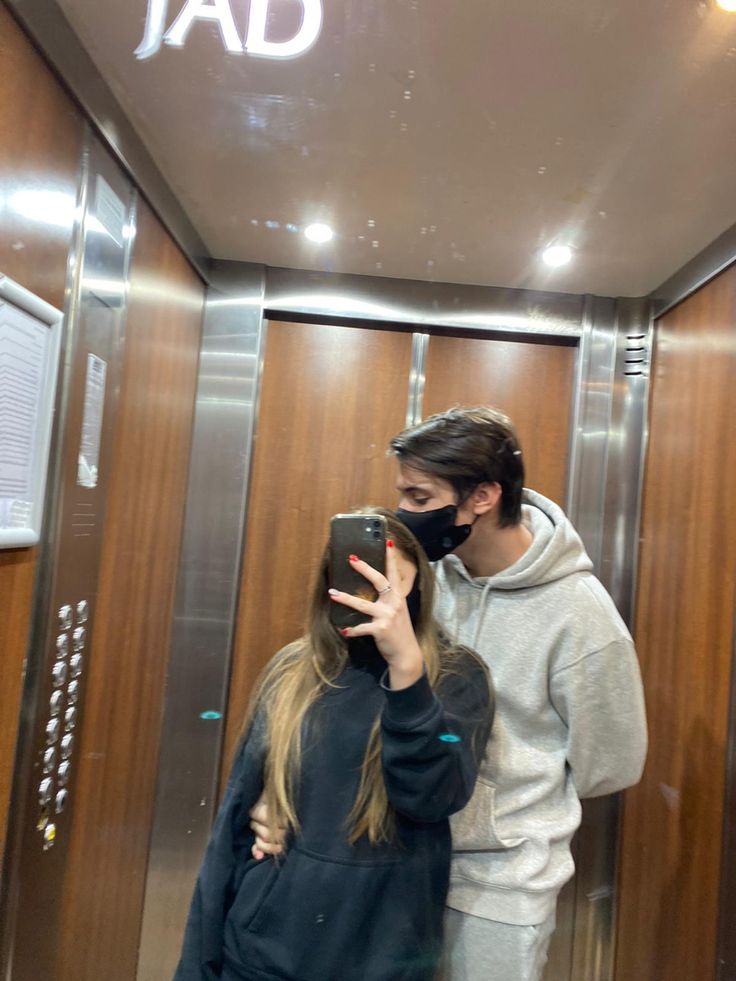 a man and woman taking a selfie in front of an elevator with the word dad written on it