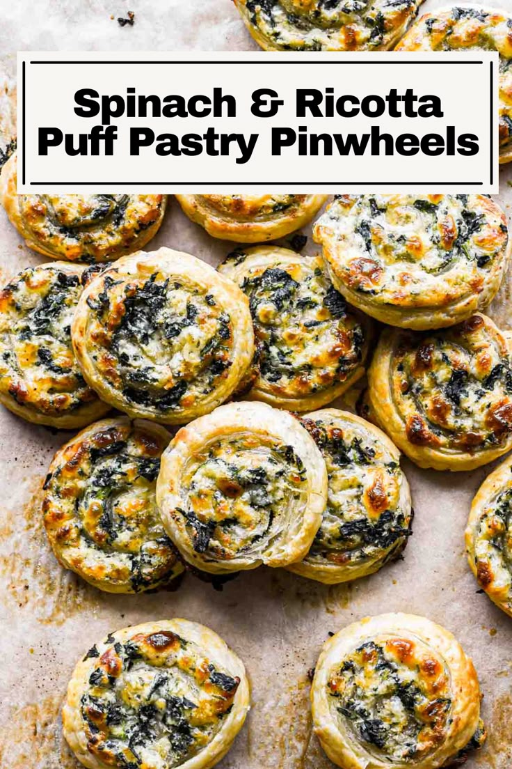 several small pastries on a baking sheet with cheese and spinach in the middle