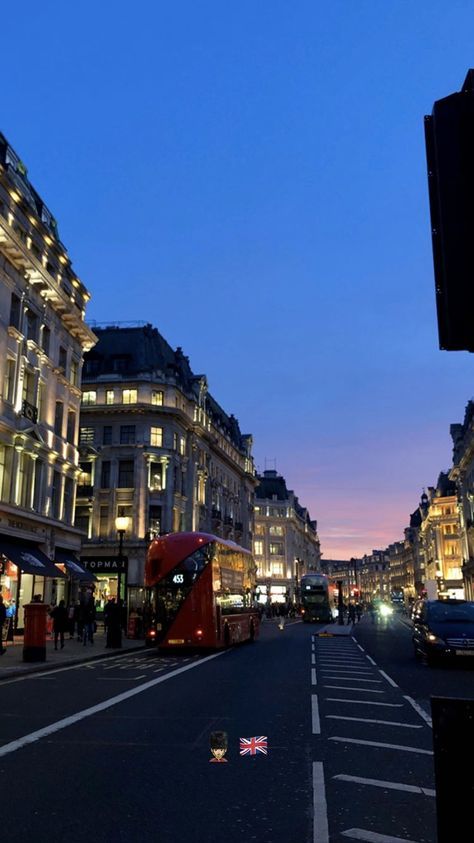 a city street at dusk with cars and buses on the road, buildings in the background