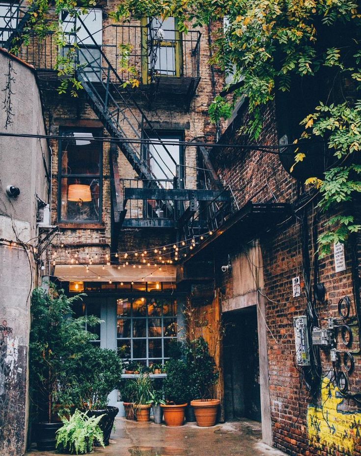 an alleyway with potted plants and stairs leading up to the second story window