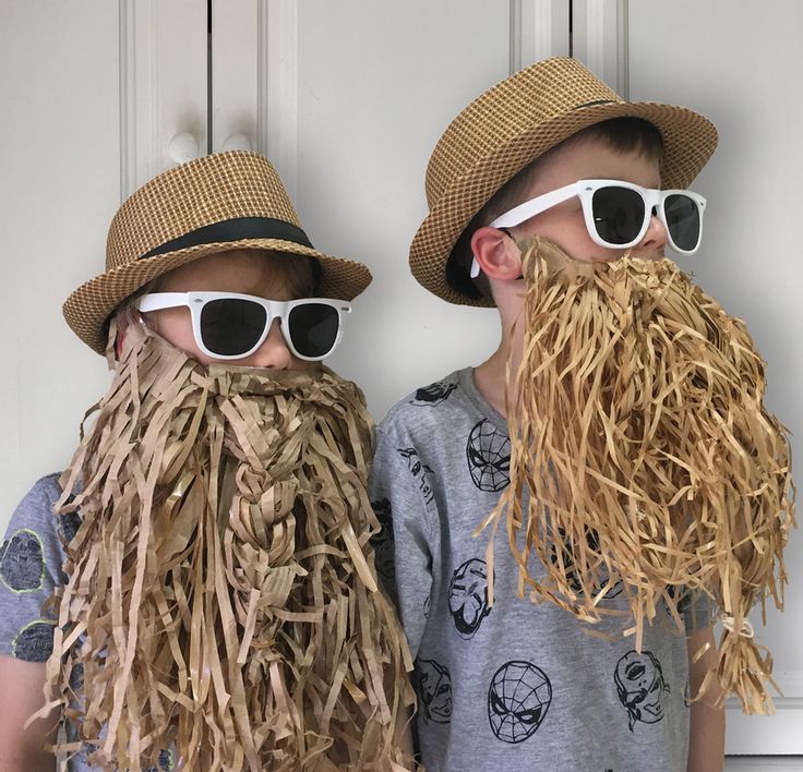 two boys wearing straw hats and sunglasses with fake grass on their heads, standing next to each other