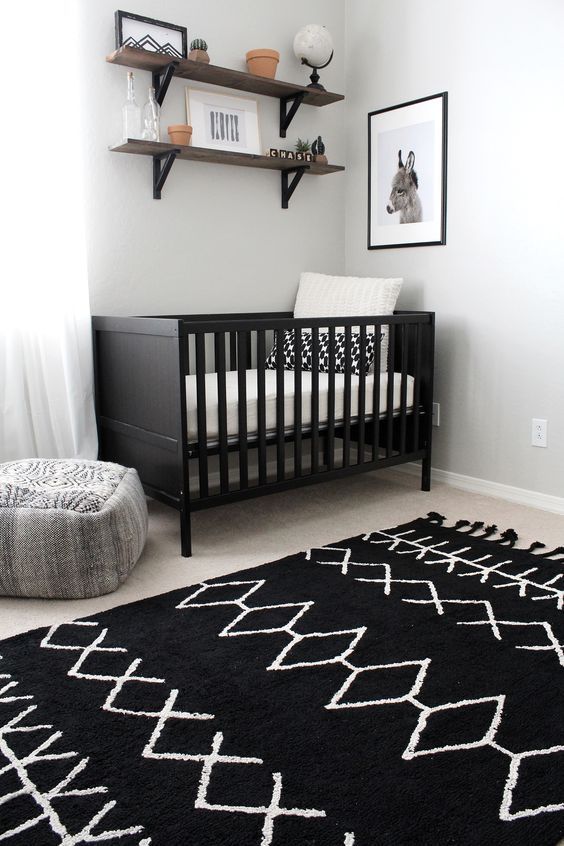 a baby's room with a black and white rug on the floor next to a crib