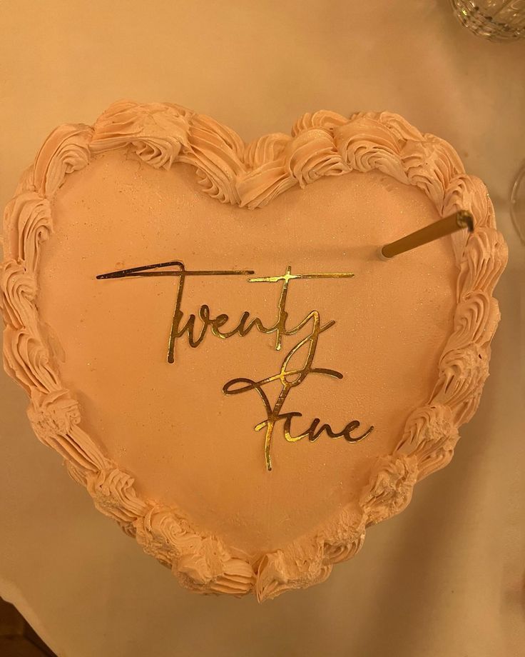 a cake shaped like a heart with the words twenty five written in gold on it