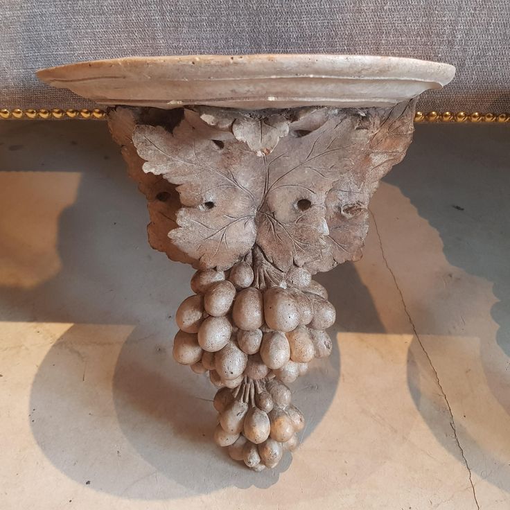 a bunch of grapes hanging from the side of a table with leaves and nuts attached to it