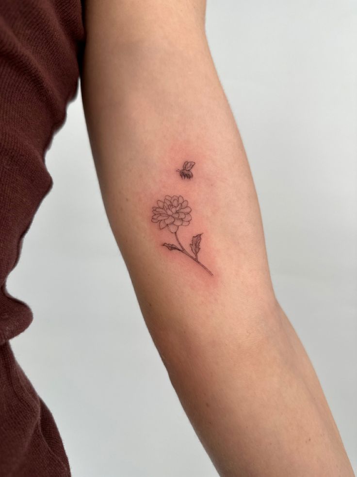 a woman's arm with a small flower tattoo on the left side of her arm