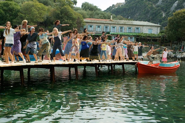 a group of people are standing on a dock with their arms in the air as they dance