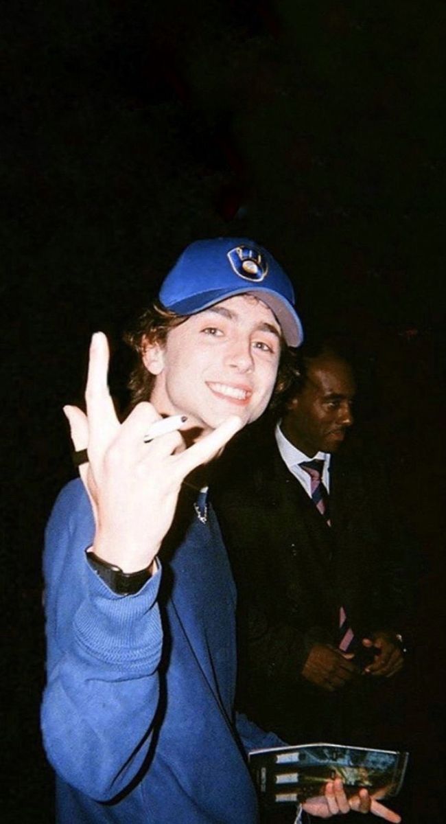 a man in a blue hat making the peace sign