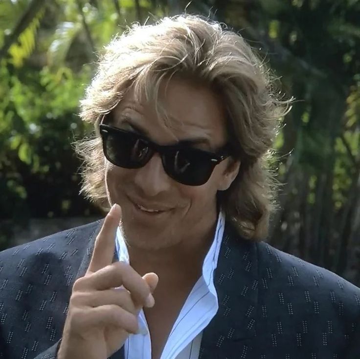 a man wearing sunglasses and pointing to the side with his finger in front of him