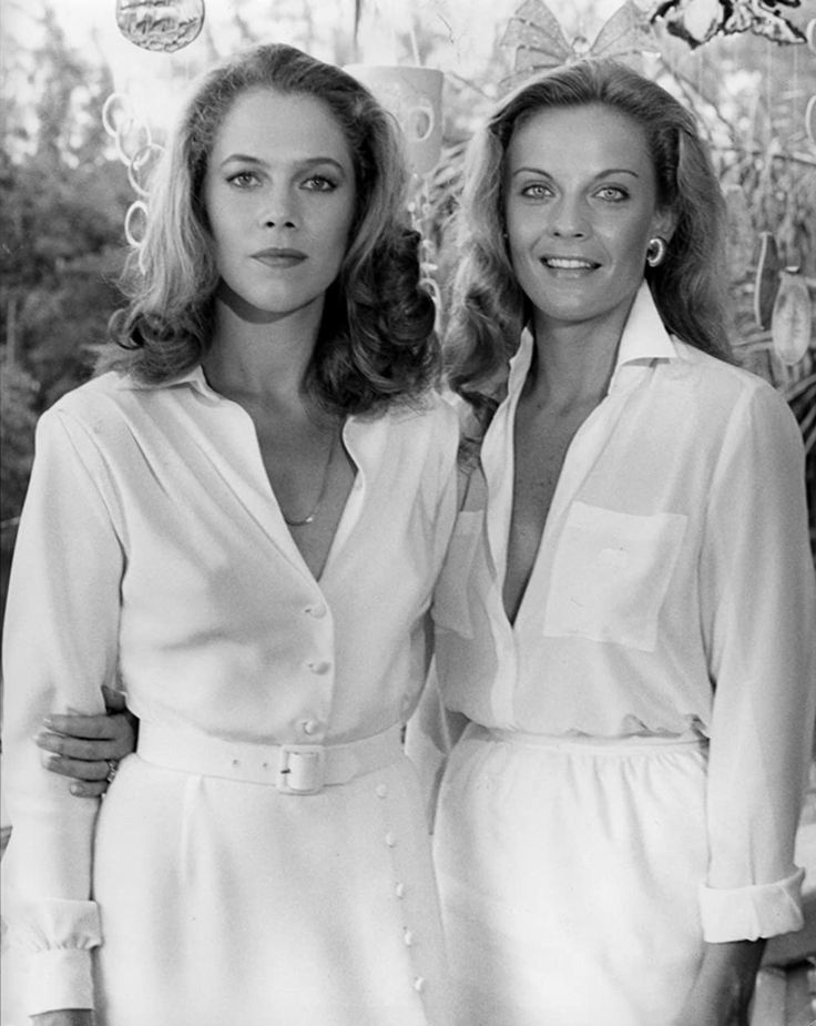 two women standing next to each other in front of a tree with decorations on it