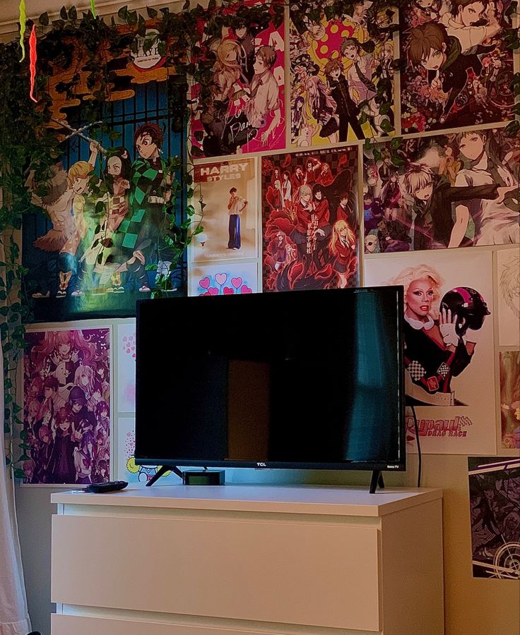 a flat screen tv sitting on top of a white dresser next to a wall covered in comic books