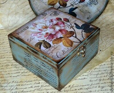 two decorative boxes sitting on top of a piece of paper with flowers painted on them