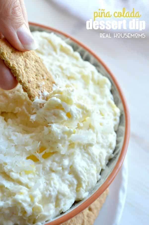 a person dipping something into a bowl of mashed potatoes with a graham cracker