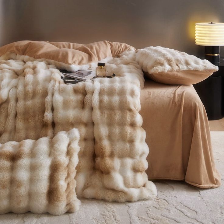 a bed covered in blankets and pillows next to a lamp