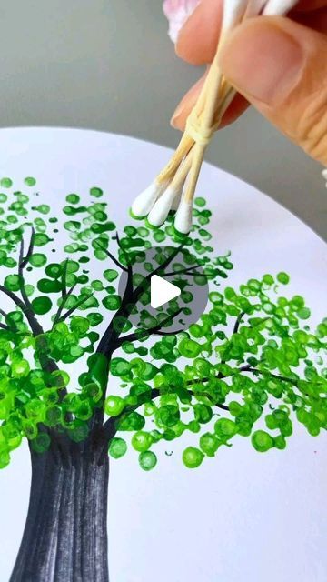 someone is painting a tree with green leaves on a white plate and it looks like they are going to paint