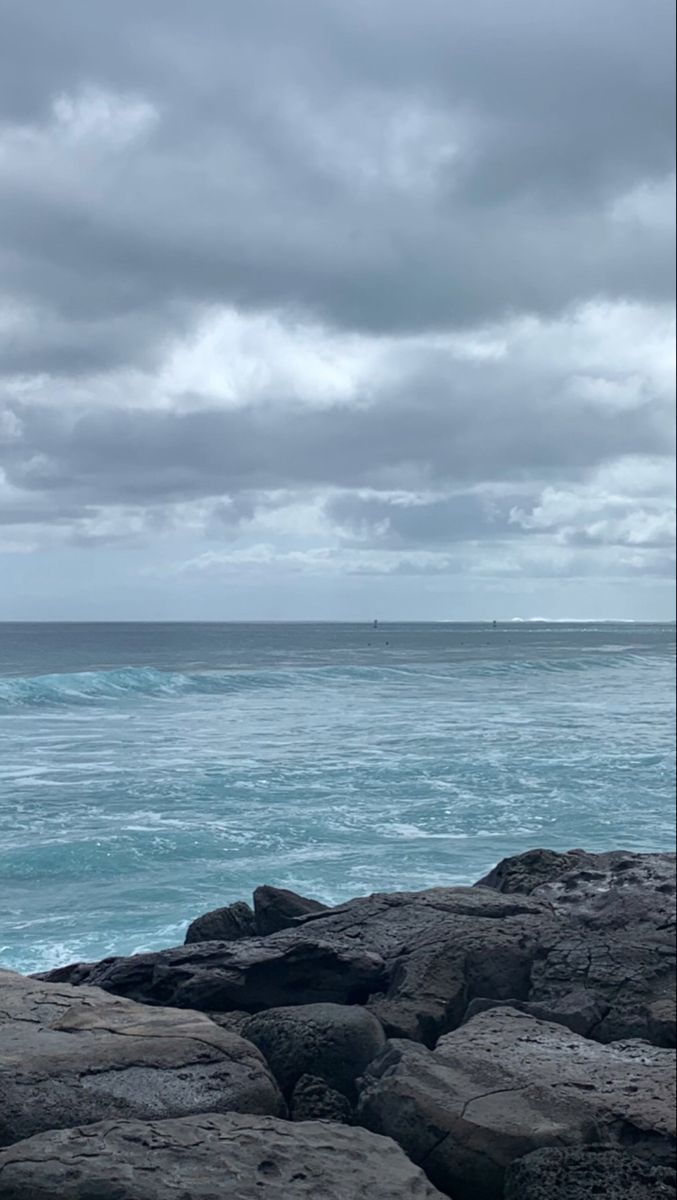 a person standing on rocks looking out at the ocean