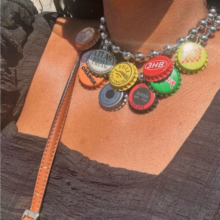 a woman wearing a brown leather necklace with various colored bottle caps on the front and back of her neck