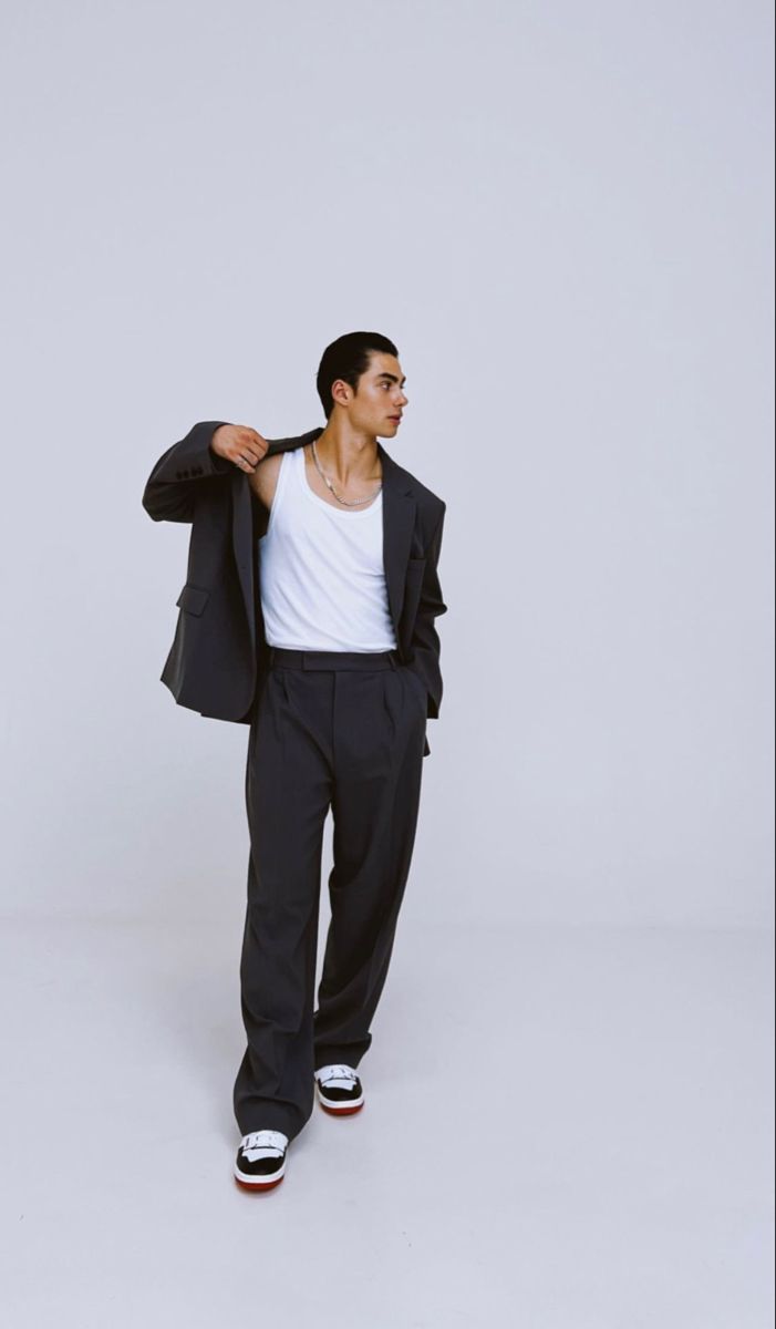 a man in black pants and a white shirt is holding his jacket over his shoulder