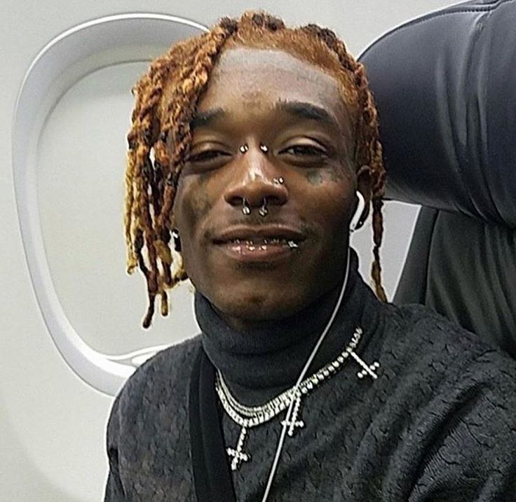 a man with dreadlocks on his head sitting in front of an airplane seat