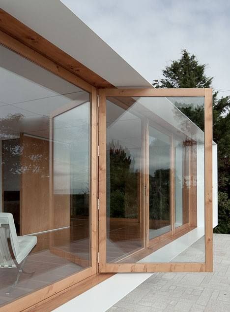 a white chair sitting on top of a patio next to a wooden structure with glass walls