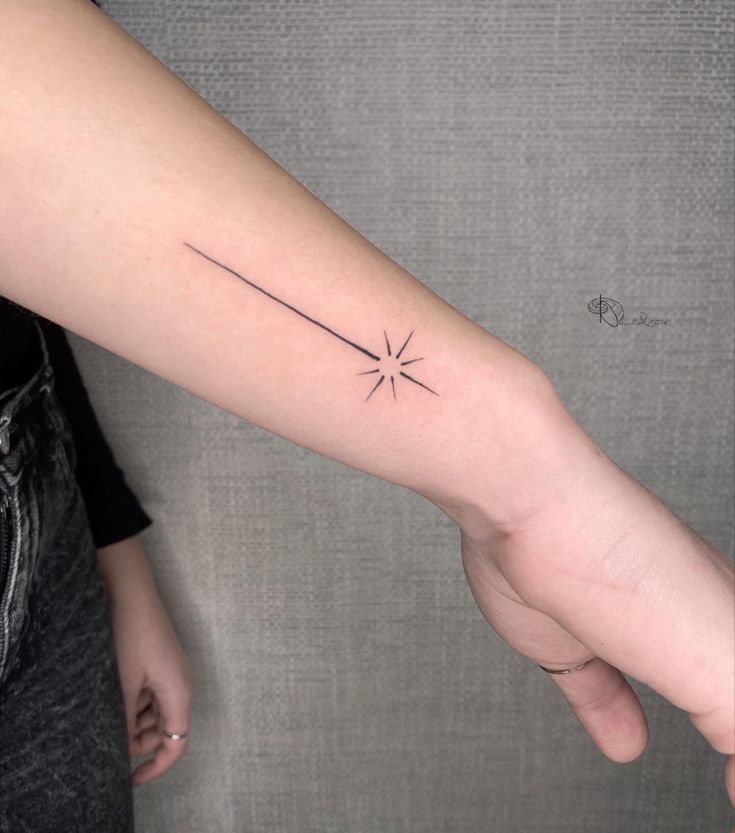 a woman's arm with a small star tattoo on it