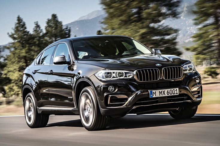 a black bmw suv driving down the road