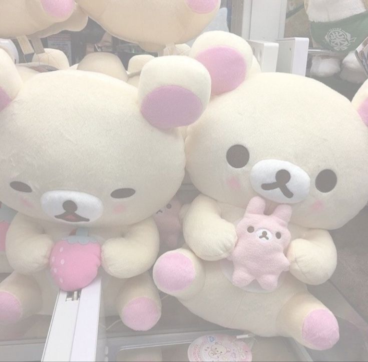 there are many pink teddy bears in the window display with one holding a baby bear