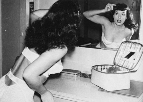 a woman brushing her hair in front of a mirror