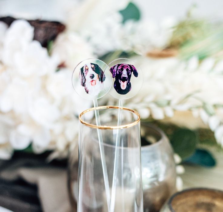 two glass vases with stickers on them sitting on a table next to flowers