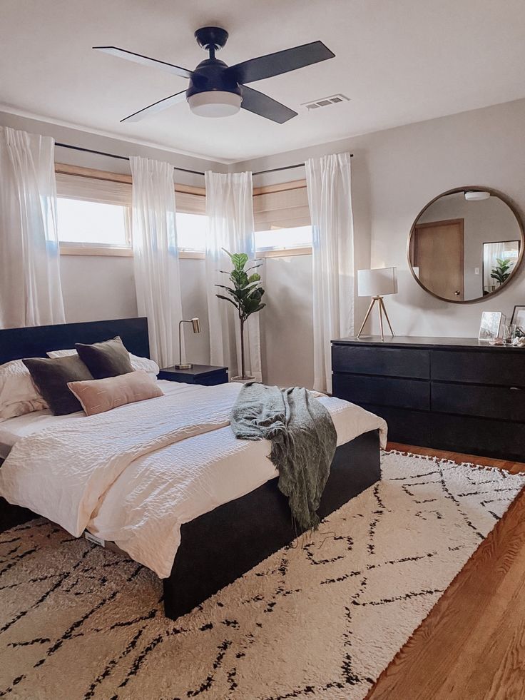 a bedroom with a bed, dresser and ceiling fan in the middle of the room