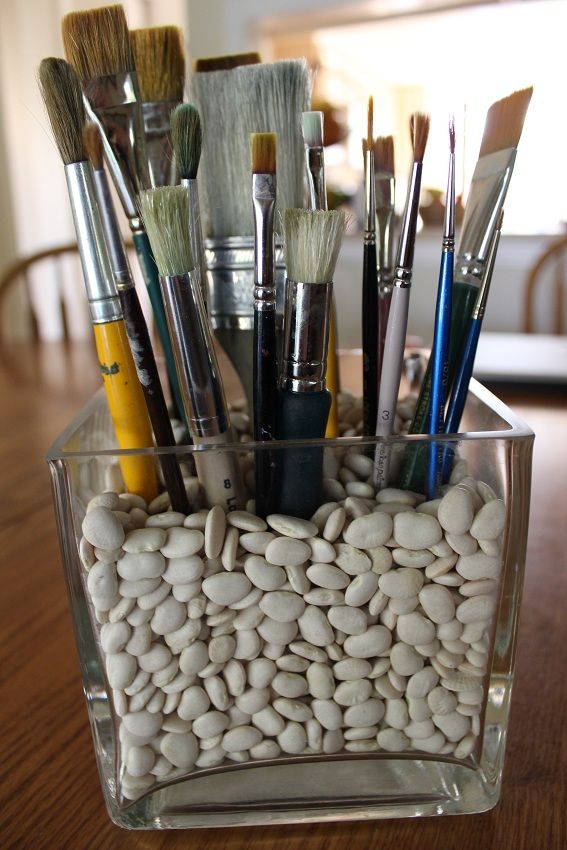 a glass container filled with lots of different types of paintbrushes and other art supplies