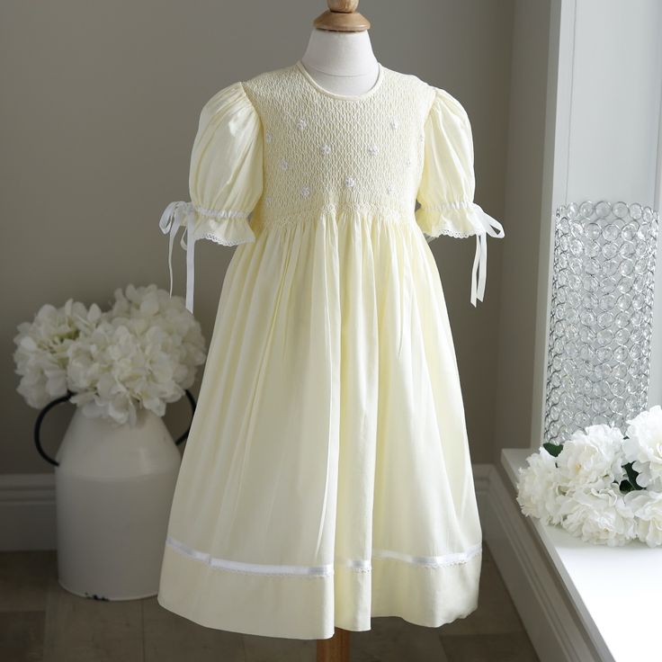 This Gorgeous Strasburg Pastel Pale Yellow Hand-Smocked Girls Float Style Dress Is In Perfect Condition. The Bodice Is Completely Hand Smocked In Yellow And White And Has White Embroidered Flower Details With Yellow Centers. The Gathered Puff Sleeves Are Trimmed In White Satin Ribbon Which Ties In A Bow And Are Finished Off With A Delicate Crocheted Cotton Lace. The Skirt Has A Lovely White Satin Ribbon Band With An Attached Delicate Crocheted Cotton Lace Trim. The Dress Is Fully Lined And Has A Button Back Closure With A Sash That Ties Into A Bow. Great For Weddings, Church, Portraits, Vacation Or Any Special Occasion. Fits Size 4/5 (See Measurements For Fit). Matching Sister/Cousin Dresses Matching Sisters, Hand Smock, Little Dresses, Pale Yellow, White Satin, Cotton Lace, Embroidered Flowers, Kids' Dresses, Satin Ribbon