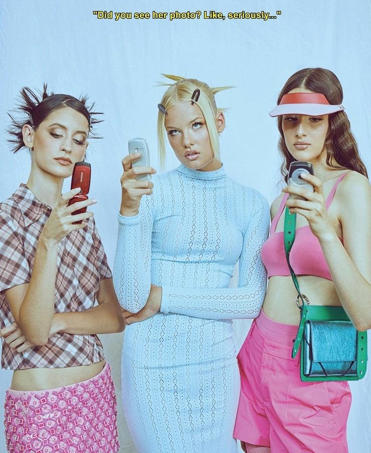 three women standing next to each other with cell phones in their hands and one holding a purse