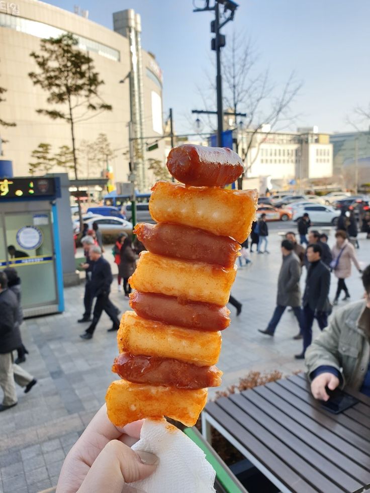 a person holding up a large stack of bacon wrapped donuts in front of them