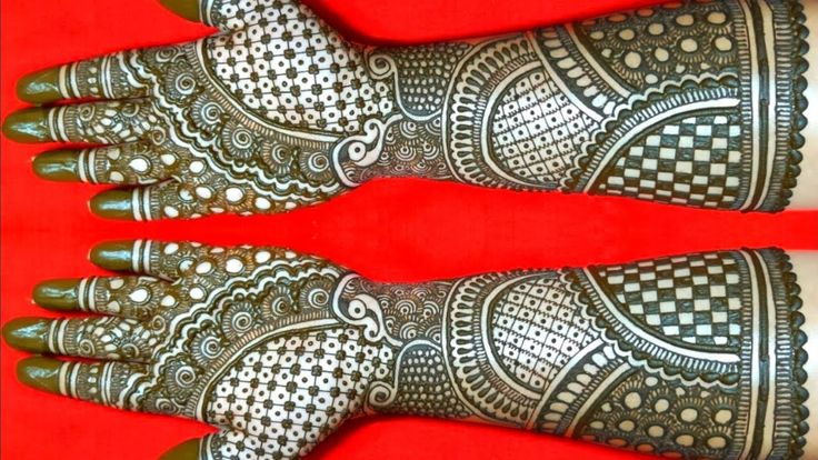 two hands that are decorated with henna designs on red background, close up photo