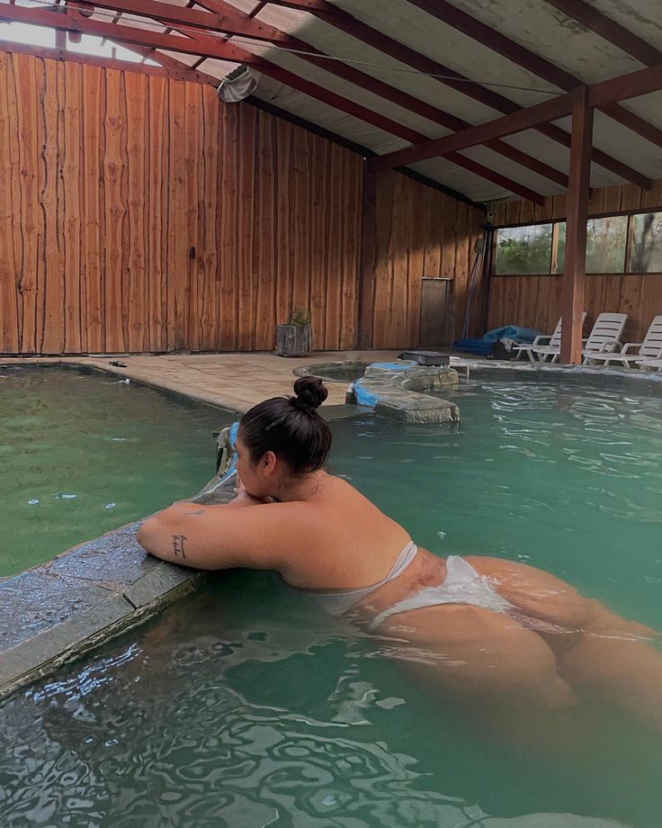 a woman in a swimming pool with her head resting on the edge of the water