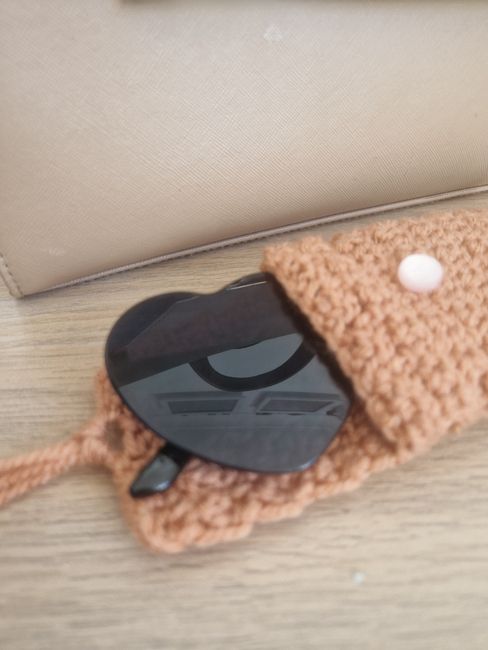 a crocheted cell phone case with a black face on the front and side