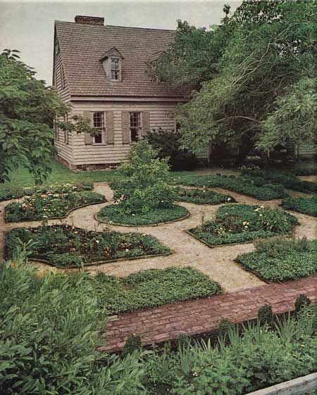 an old house surrounded by greenery in the middle of a garden with a path leading to it